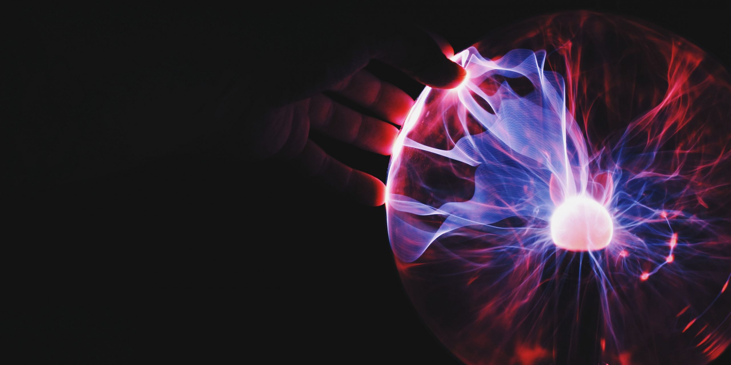 A hand touching a glowing plasma globe - the original ThinkGeniux Creating Beyond image
